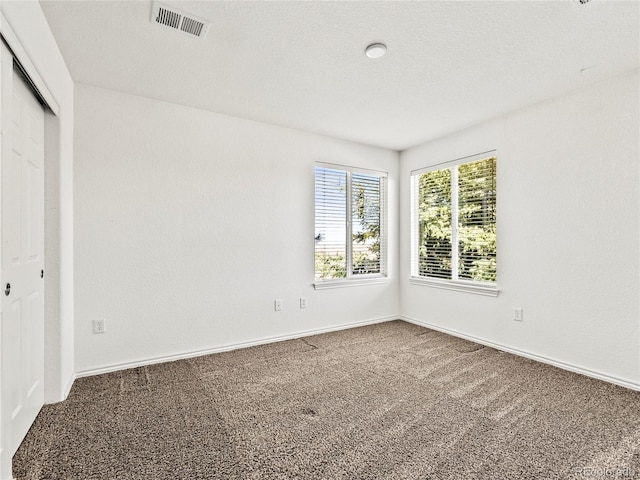 carpeted empty room featuring a textured ceiling