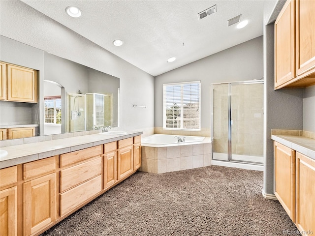 bathroom featuring lofted ceiling, vanity, independent shower and bath, and a textured ceiling