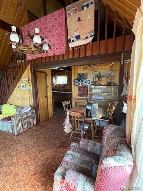 interior space featuring wood walls, carpet, sink, and high vaulted ceiling