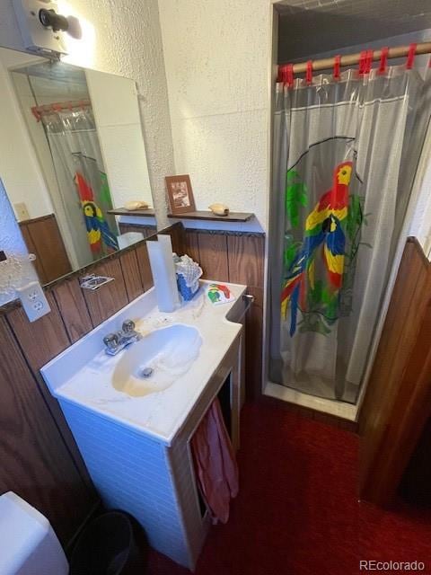 bathroom featuring toilet, vanity, and a shower with curtain