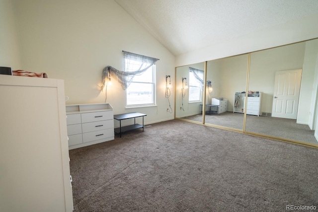 unfurnished bedroom with a closet, carpet flooring, a textured ceiling, and lofted ceiling