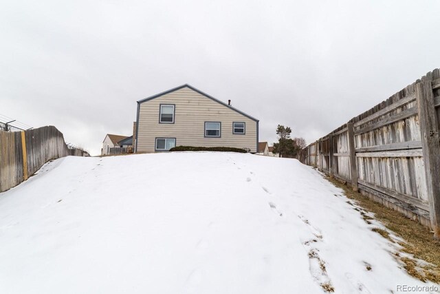 view of snow covered back of property