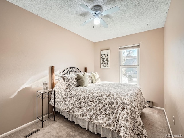 bedroom with ceiling fan, carpet, and a textured ceiling