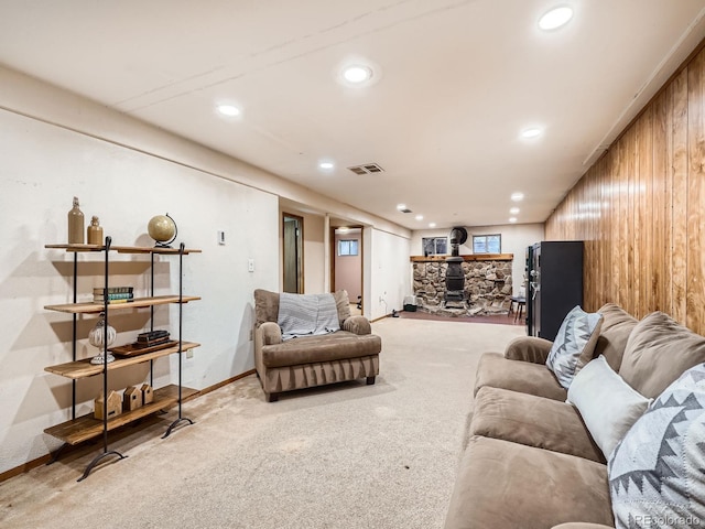 living room featuring wooden walls, a wood stove, and light colored carpet