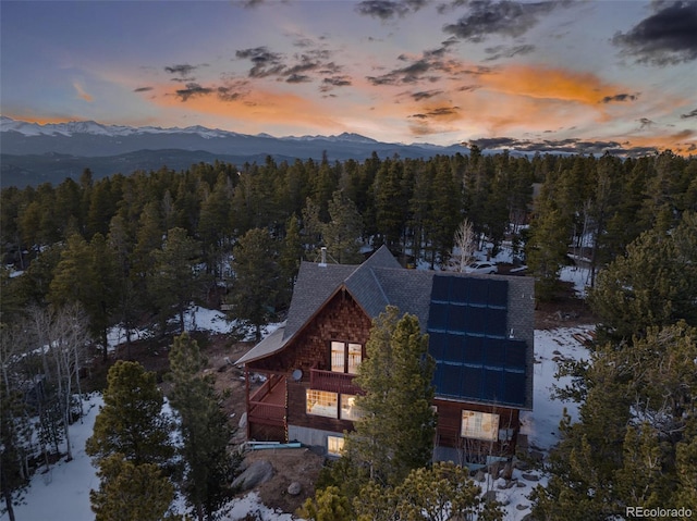 aerial view at dusk featuring a mountain view and a forest view