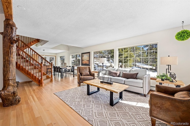 living room with stairway, baseboard heating, a textured ceiling, and hardwood / wood-style floors