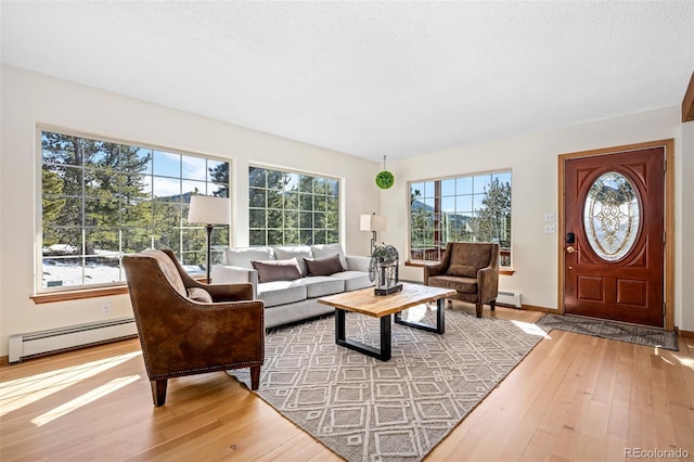 living area with a textured ceiling, baseboard heating, and hardwood / wood-style flooring