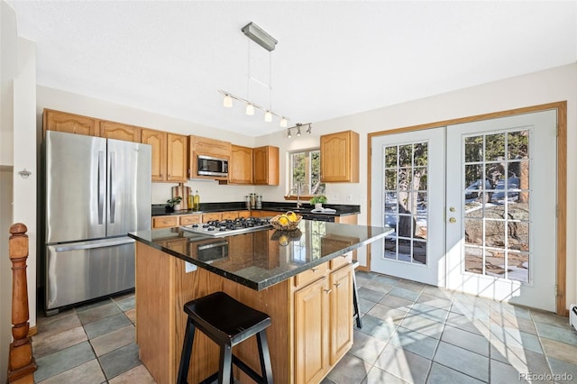 kitchen with a breakfast bar, a sink, stainless steel appliances, decorative light fixtures, and a center island