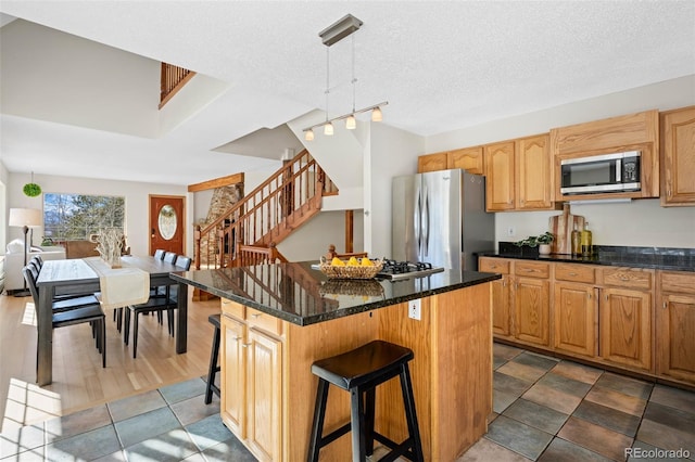 kitchen featuring a kitchen island, pendant lighting, a breakfast bar area, stainless steel appliances, and a textured ceiling