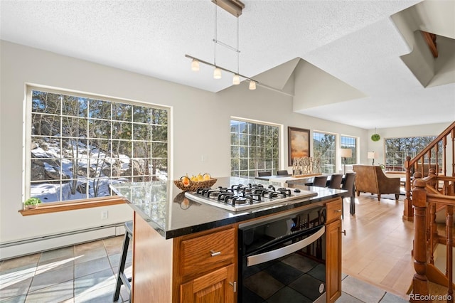439 Ronnie Rd, Golden, CO 80403 - kitchen featuring oven, stainless steel gas stovetop, a baseboard heating unit, a textured ceiling, and brown cabinetry