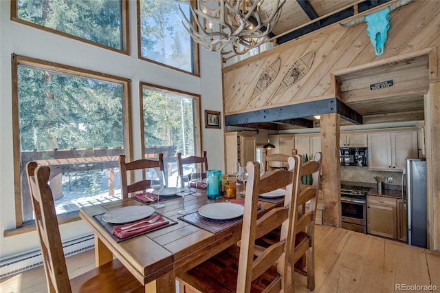 68 Starlit Ln, Blue River, CO 80424 - dining room with light wood-style floors, a high ceiling, wood walls, a baseboard radiator, and a notable chandelier