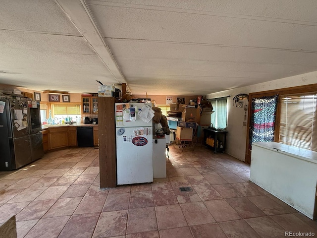 kitchen with tile patterned floors, a textured ceiling, stainless steel refrigerator, white refrigerator, and dishwasher