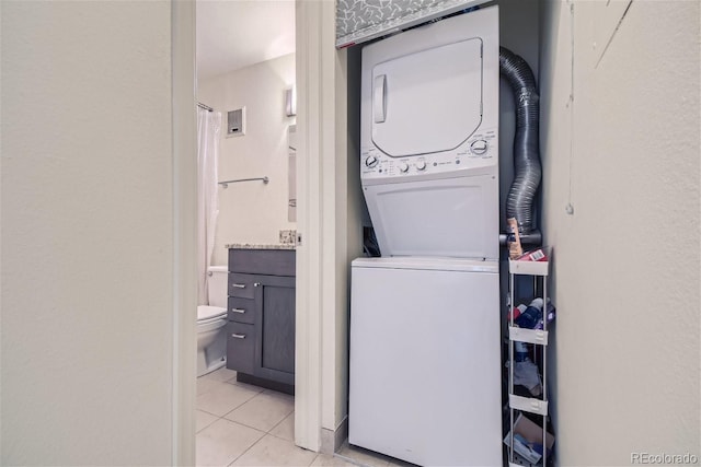 laundry area featuring stacked washer and dryer and light tile patterned floors