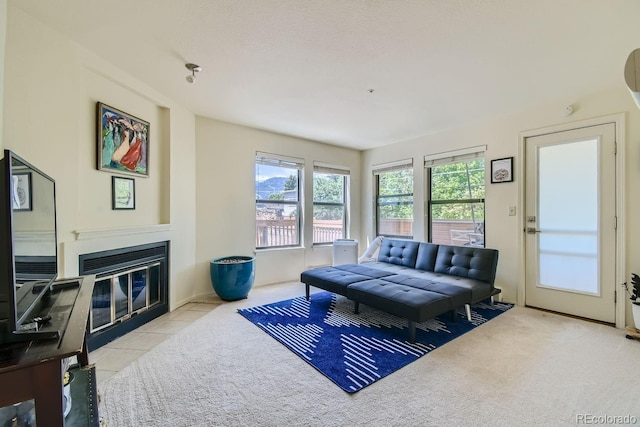 living room featuring a tiled fireplace, light tile patterned floors, and a textured ceiling