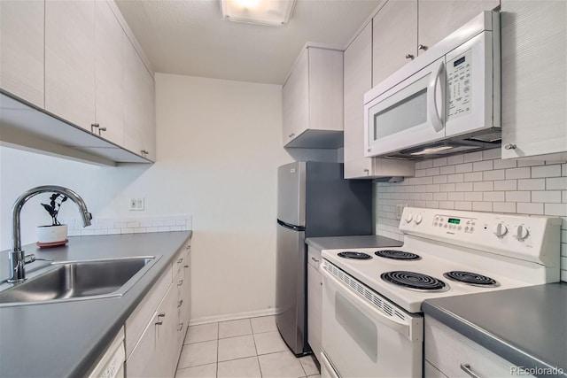 kitchen featuring light tile patterned flooring, sink, white cabinets, backsplash, and white appliances