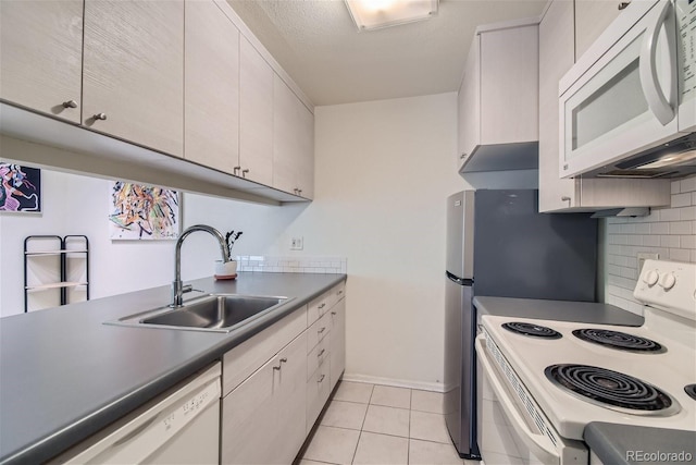 kitchen with sink, white appliances, light tile patterned floors, tasteful backsplash, and a textured ceiling