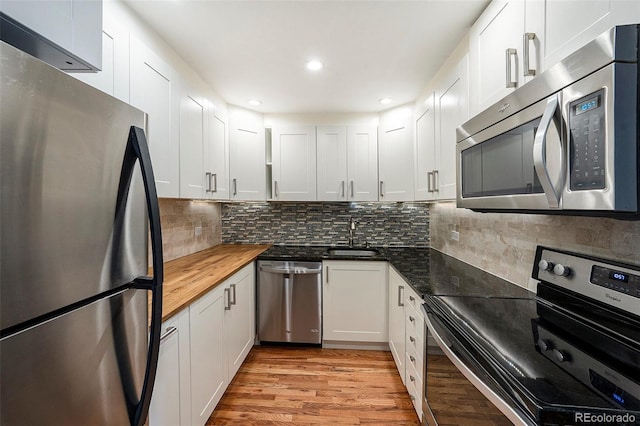 kitchen featuring sink, appliances with stainless steel finishes, butcher block counters, white cabinets, and light wood-type flooring