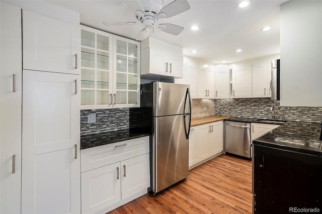 kitchen featuring white cabinetry, ceiling fan, stainless steel appliances, light hardwood / wood-style floors, and decorative backsplash