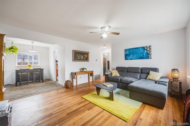 living room with wood finished floors, visible vents, and a ceiling fan