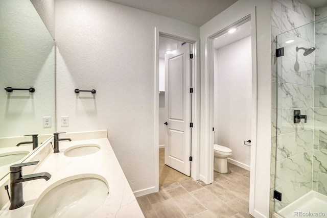 bathroom featuring toilet, a stall shower, double vanity, and a sink