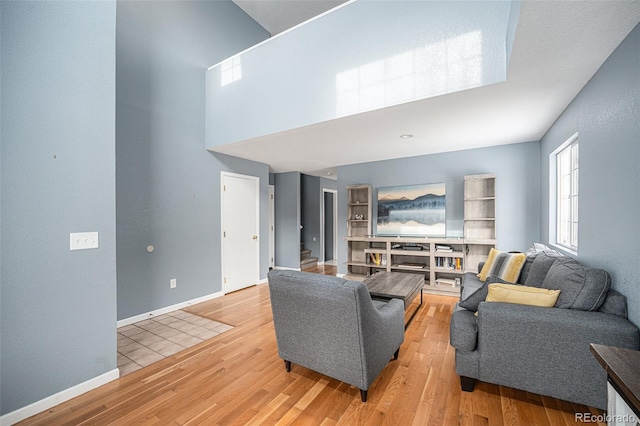 living area with a high ceiling, baseboards, and wood finished floors