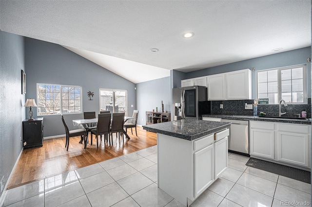 kitchen with white cabinets, stainless steel appliances, a sink, and a center island