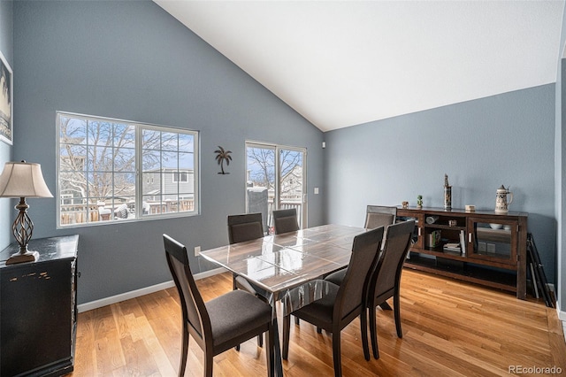 dining space with high vaulted ceiling, light wood-style flooring, and baseboards