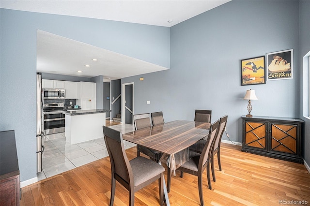 dining space featuring light wood finished floors, stairway, and baseboards