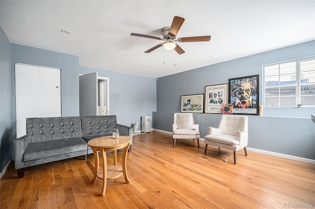 living area with light wood-type flooring, ceiling fan, and baseboards