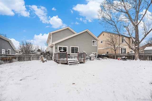 snow covered back of property with fence private yard and a wooden deck