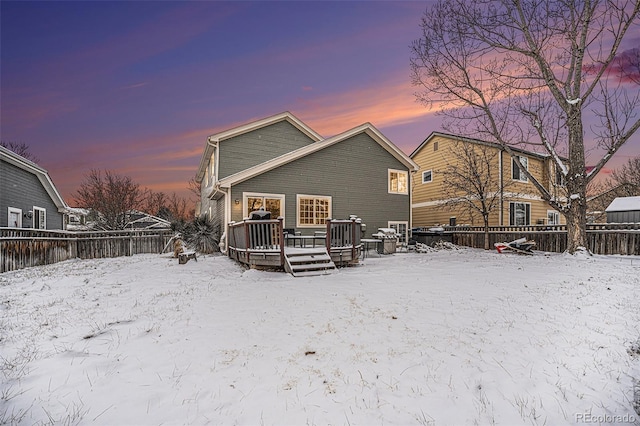 snow covered house featuring fence and a wooden deck