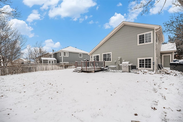 snow covered rear of property featuring fence and a deck