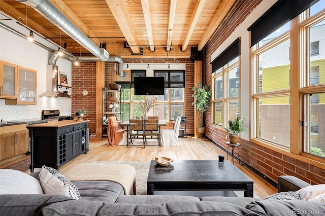 2955 Inca St Unit 2P, Denver, CO 80202 - living area featuring brick wall, light wood finished floors, rail lighting, and a wooden ceiling with exposed beams