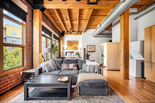 2955 Inca St Unit 2P, Denver, CO 80202 - living room with stacked washer / drying machine, wood finished floors, a wooden ceiling with exposed beams, and brick wall