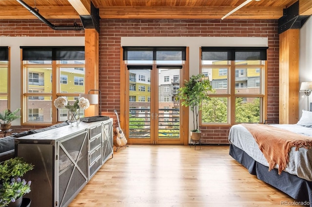 2955 Inca St Unit 2P, Denver, CO 80202 - bedroom featuring a wooden ceiling with exposed beams, brick wall, light wood-style flooring, and access to outside