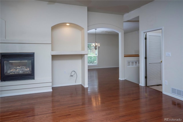 unfurnished living room featuring hardwood / wood-style floors, a multi sided fireplace, and a chandelier