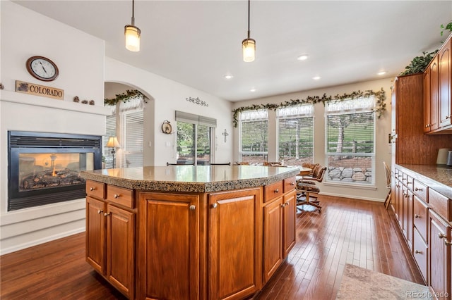 kitchen featuring a multi sided fireplace, a center island, pendant lighting, and dark hardwood / wood-style floors