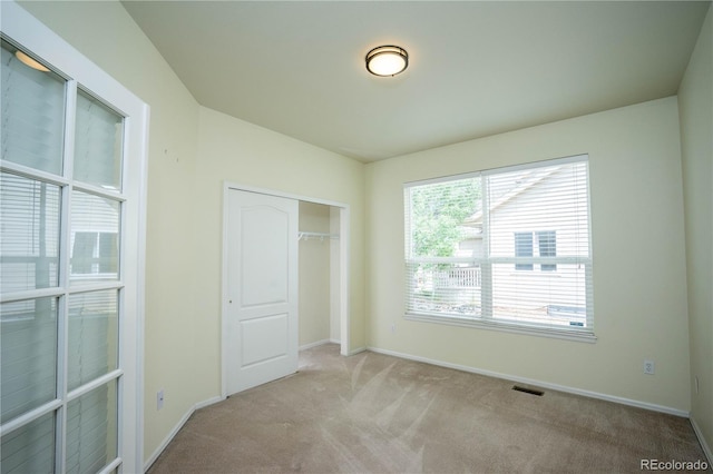 unfurnished bedroom with a closet and light carpet