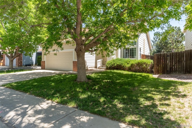 view of property hidden behind natural elements featuring driveway, an attached garage, and brick siding