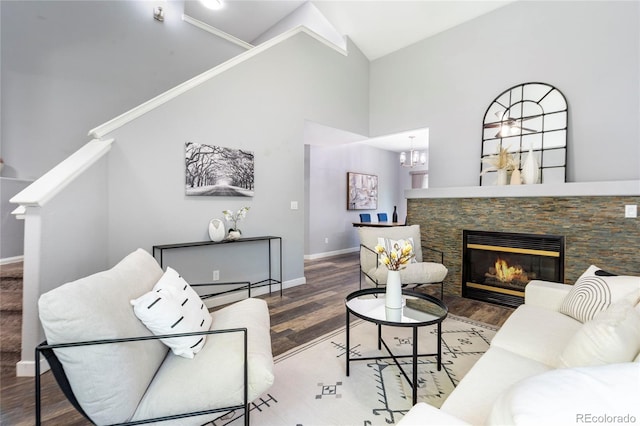living area featuring wood finished floors, baseboards, high vaulted ceiling, a fireplace, and stairway
