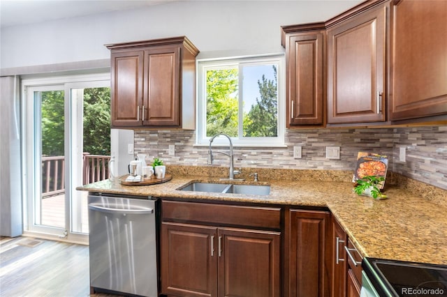 kitchen with stainless steel dishwasher, a sink, plenty of natural light, and tasteful backsplash