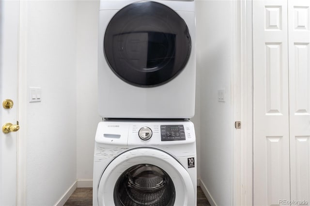 laundry area with stacked washer / dryer, baseboards, and dark wood-style floors
