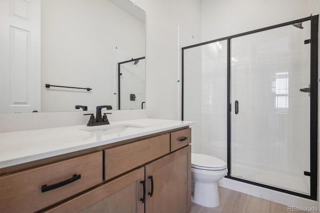 bathroom featuring toilet, vanity, a shower with shower door, and hardwood / wood-style flooring