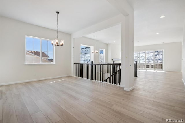 spare room featuring light wood-type flooring and a notable chandelier