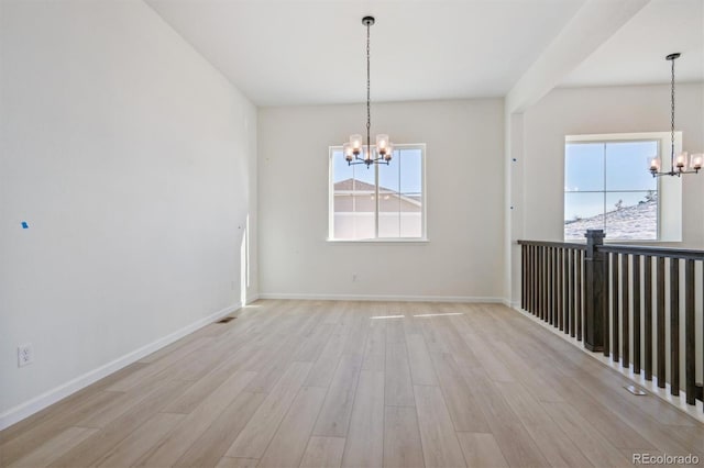 unfurnished dining area featuring light hardwood / wood-style flooring, a healthy amount of sunlight, and a notable chandelier