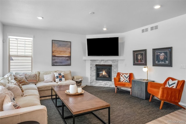 living room with visible vents, recessed lighting, a glass covered fireplace, and wood finished floors