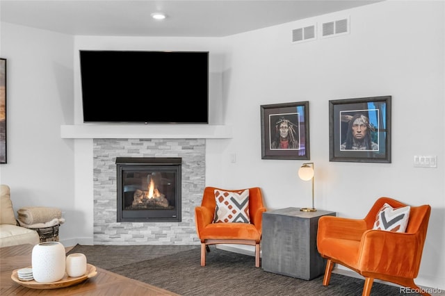 sitting room featuring baseboards, a stone fireplace, and visible vents