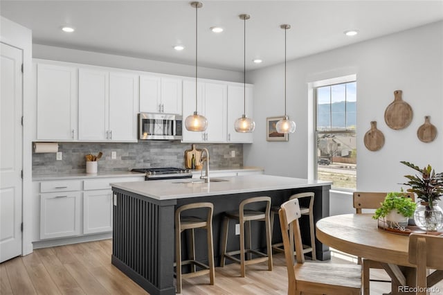kitchen with backsplash, range, stainless steel microwave, and a sink