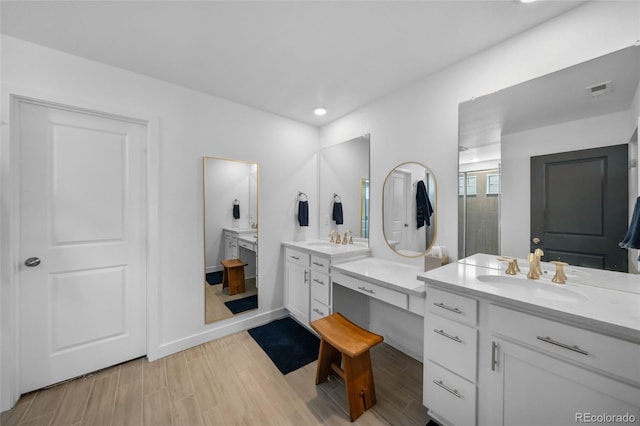bathroom featuring visible vents, two vanities, a sink, and wood finished floors