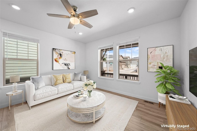 living area with visible vents, wood finished floors, and a healthy amount of sunlight